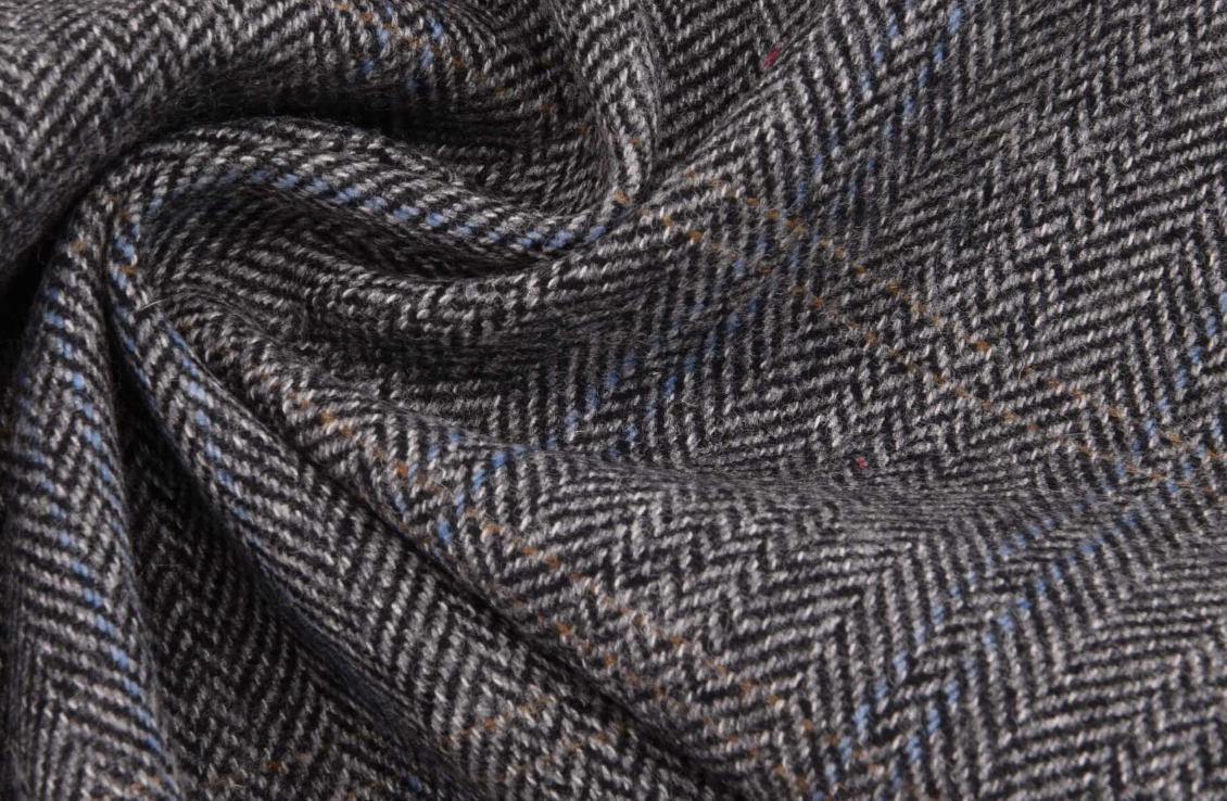 Close-up of herringbone patterned fabric in brown and gray tones.