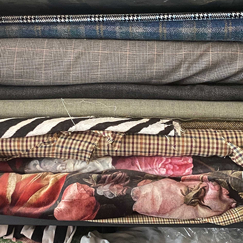 Stack of various fabric swatches including floral, checkered, and striped pattern