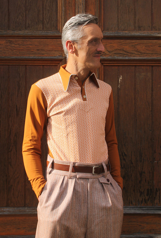 rust brown long sleeve polo shirt with pointed collar. The front panel is from 3D knit bio cotton with braid motif in orange and off white, the sleeves, collar and back are rust brown soft bio jersey with a french terry finish on the inside.