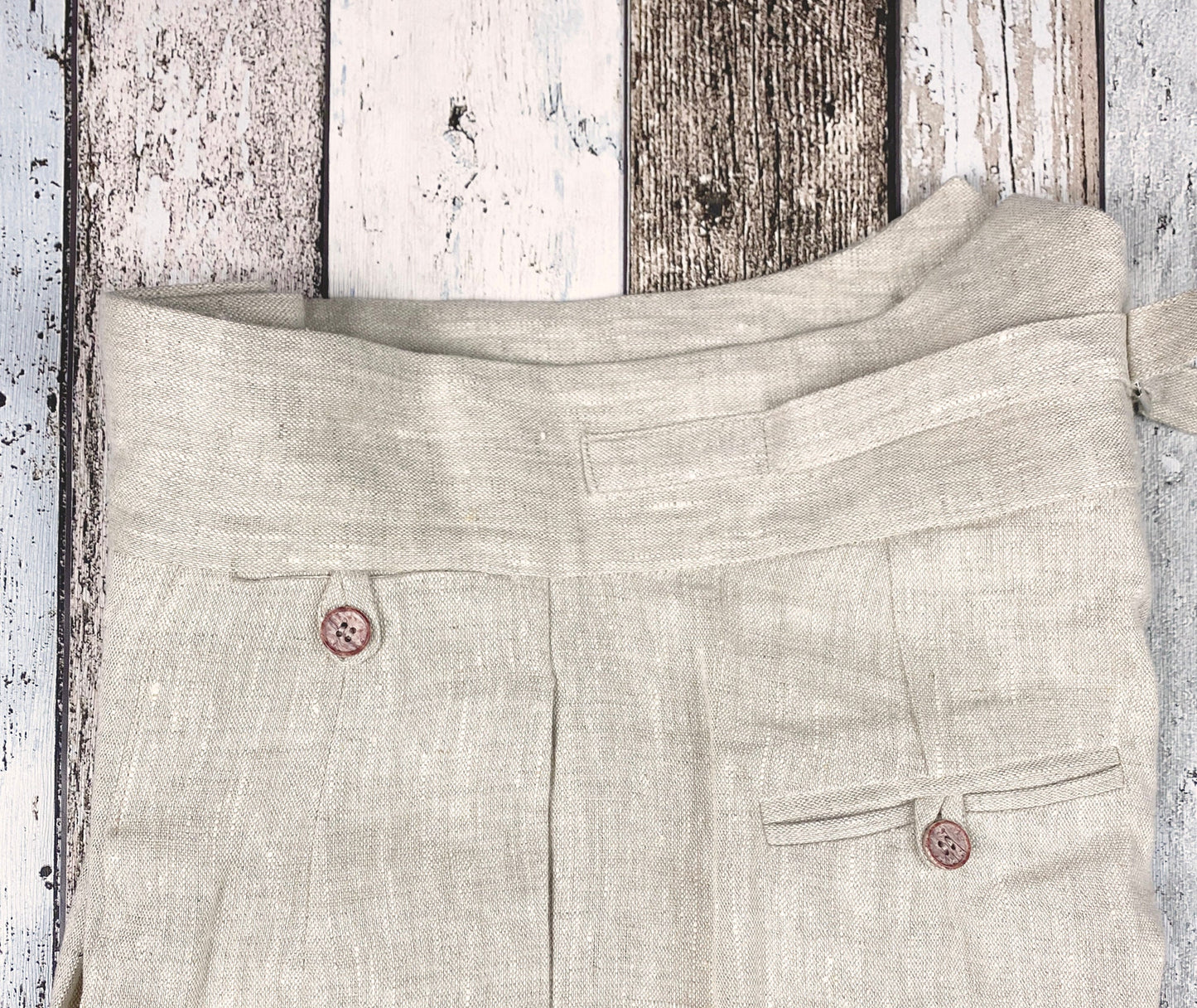 1930s style ladies suit pants for women in natural colored linen. These trousers are adapted from a 1930s mens pattern with wide fit, pleated front, very high waisted, fishtail back and buckle back. Close up from the side, showing front watch pocket with loop and button, the generous side pocket, the buckle on the back waistband and one back pocket.