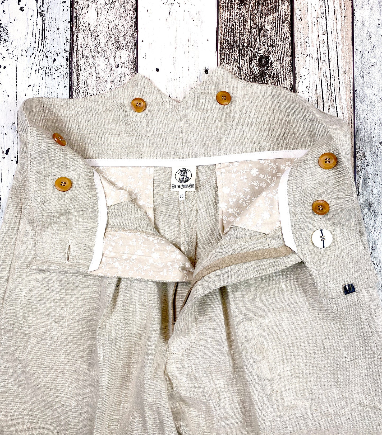 1930s style ladies suit pants for women in natural colored linen. These trousers are adapted from a 1930s mens pattern with wide fit, pleated front, very high waisted, fishtail back and buckle back. Close up inside the trousers showing the generous pockets made from printed cotton in beige with small white flowers