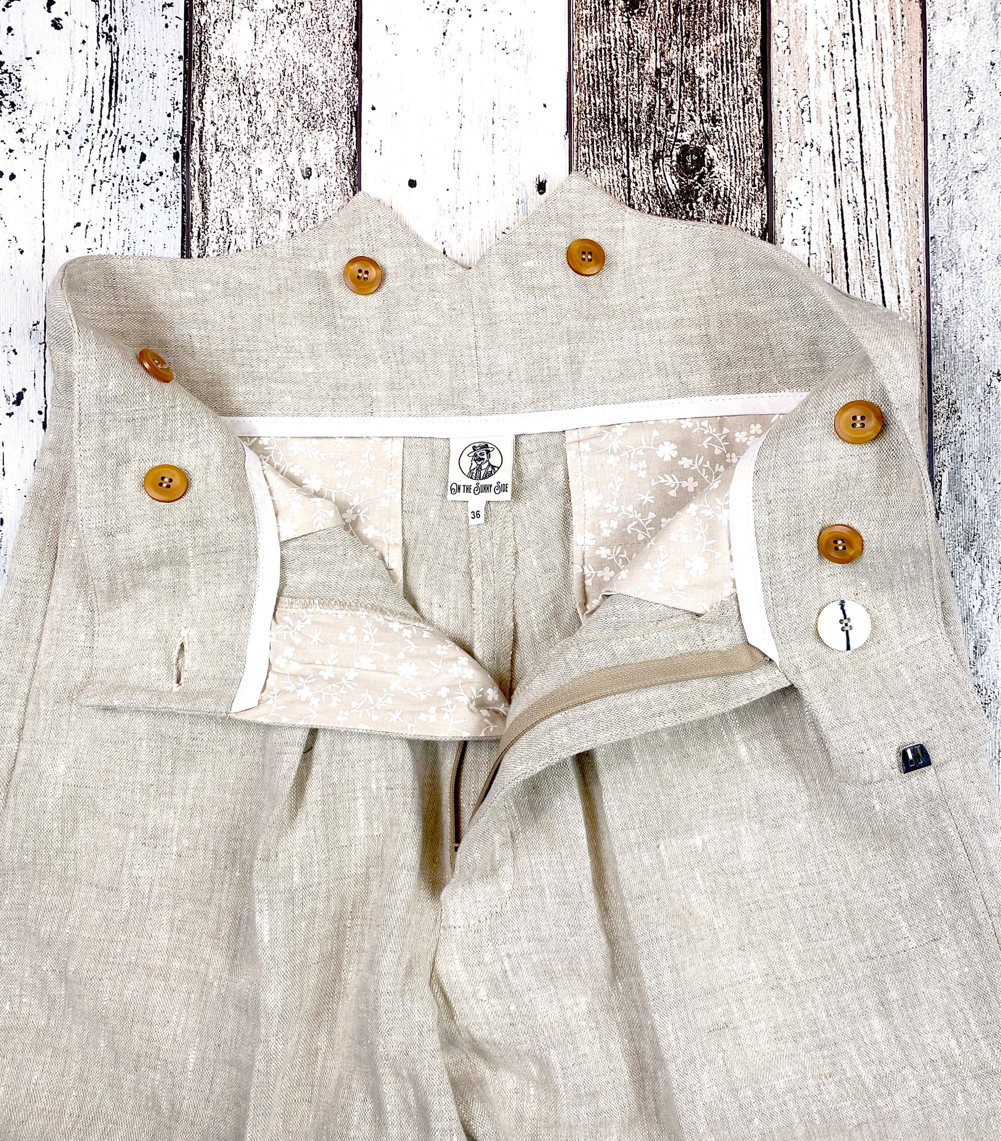 1930s style ladies suit pants for women in natural colored linen. These trousers are adapted from a 1930s mens pattern with wide fit, pleated front, very high waisted, fishtail back and buckle back. Close up inside the trousers showing the generous pockets made from printed cotton in beige with small white flowers