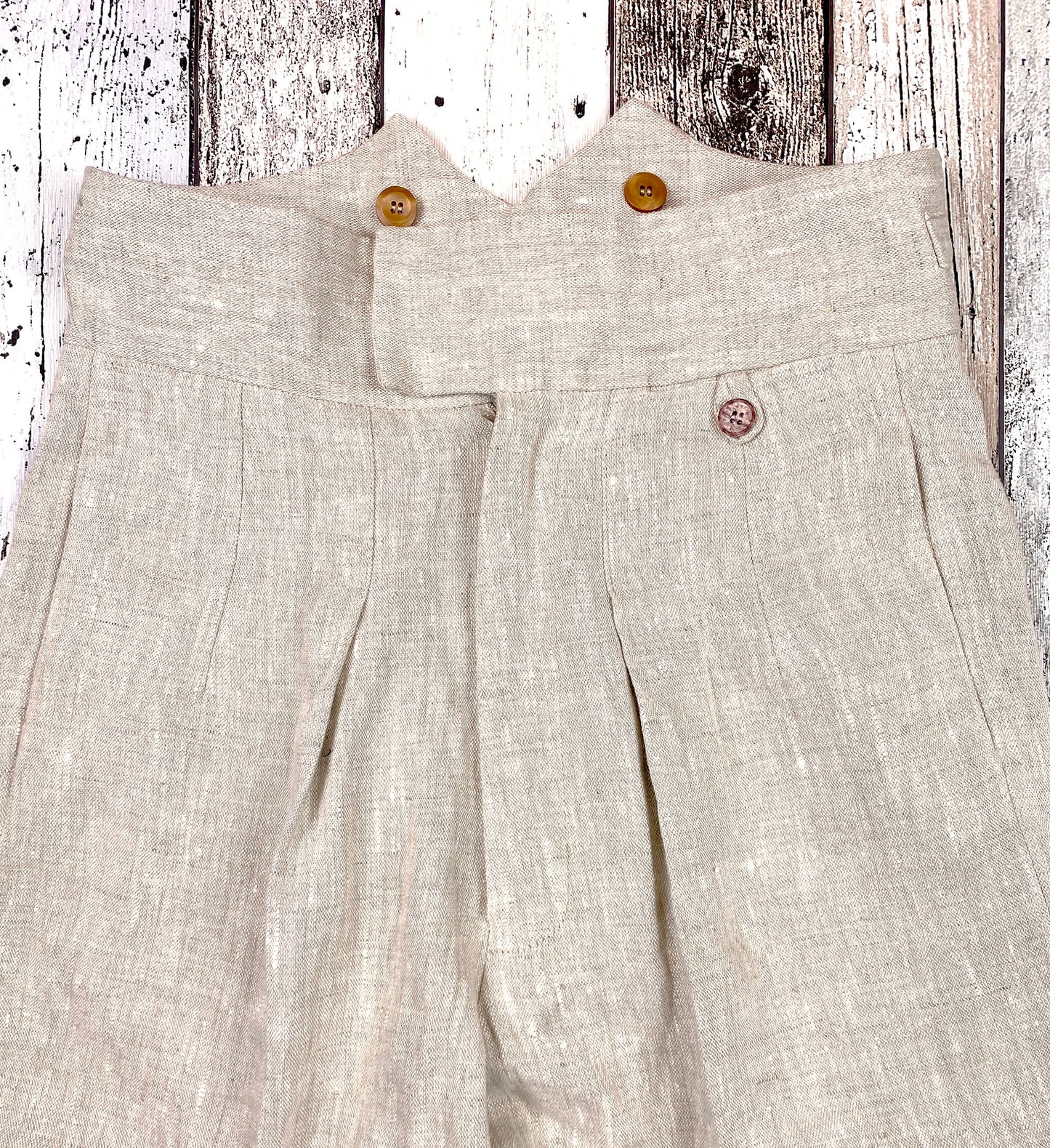 1930s style ladies suit pants for women in natural colored linen. These trousers are adapted from a 1930s mens pattern with wide fit, pleated front, very high waisted, fishtail back and buckle back. Close up front, zipper closure like men&#39;s trousers, waistband overlapped closure with hook and eye, inward folded pleats