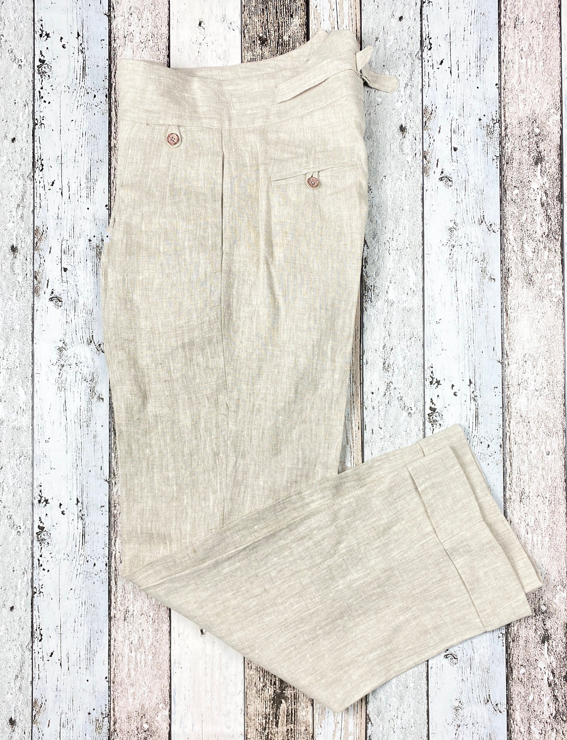 1930s style ladies suit pants for women in natural colored linen. These trousers are adapted from a 1930s mens pattern with wide fit, pleated front, very high waisted, fishtail back and buckle back. Item view from the side.