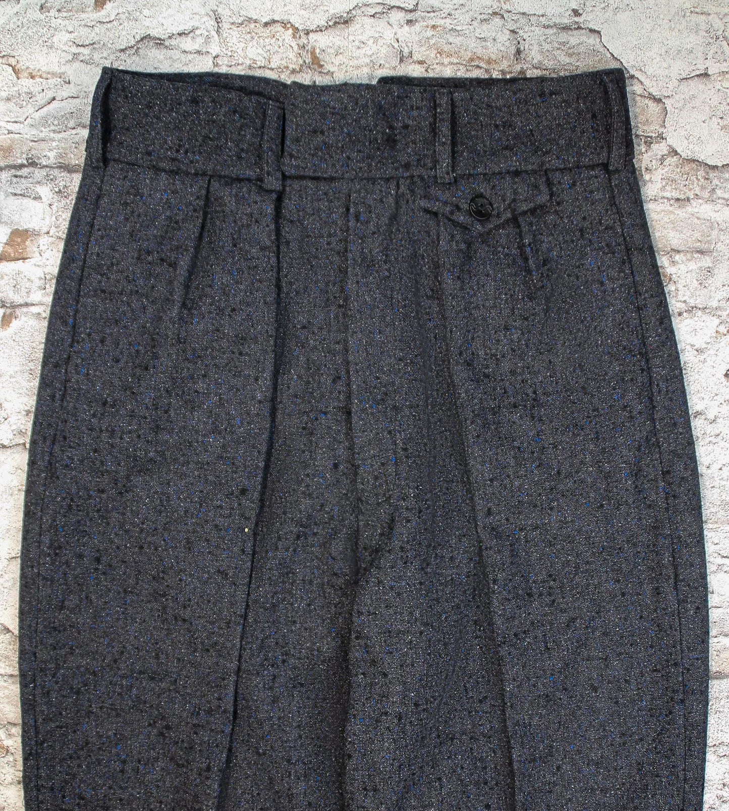 These high-waisted, pleated vintage-style trousers are made of rugged pure wool in a dark grey charcoal colour with small bright blue flecks.  The design is based on an original pattern from the 1940s with all the attention to details. Close up front view of pocket flap, waistband with belt hoops and inward folding pleats
