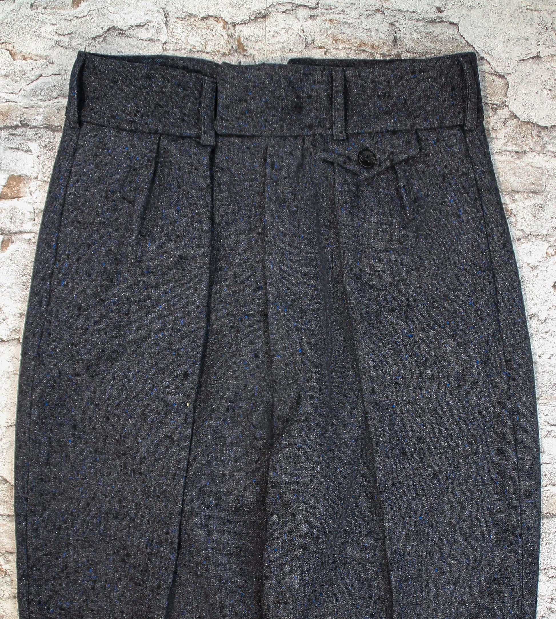These high-waisted, pleated vintage-style trousers are made of rugged pure wool in a dark grey charcoal colour with small bright blue flecks.  The design is based on an original pattern from the 1940s with all the attention to details. Close up front view of pocket flap, waistband with belt hoops and inward folding pleats
