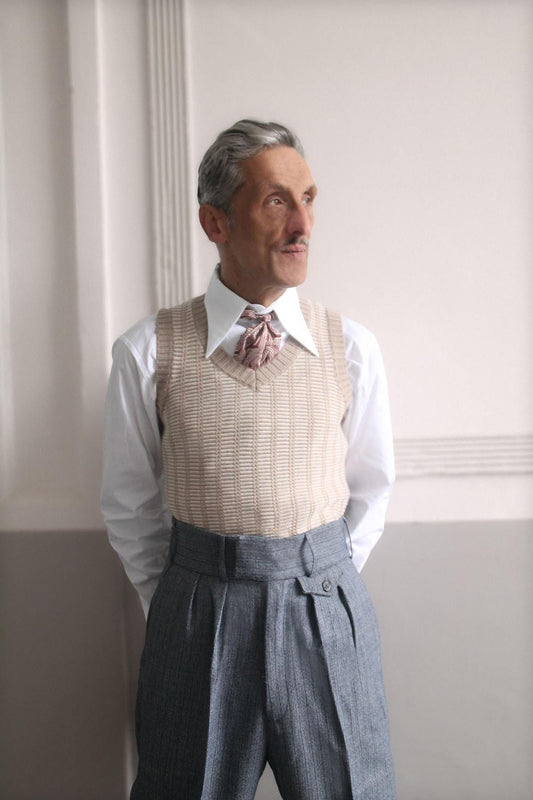 1930s style mens high waisted trousers in blue striped wool. The man is wearing a knitted tank top and a white spear point vintage style shirt with a knotted tie