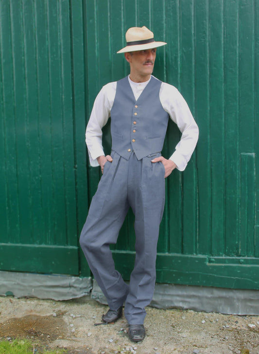 A light blue two-piece suit, comprising a waistcoat with wooden buttons, matching trousers, and a white long-sleeved shirt. The outfit is complemented by a straw hat with a black band.